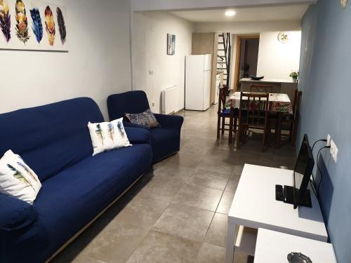 ein Wohnzimmer mit einem blauen Sofa und einer Küche in der Unterkunft Casa Castillo de la Estrella in Segorbe