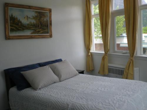 a bedroom with a bed and two windows at Chameleon Hotel in Castlegar