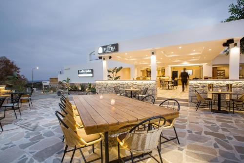 a wooden table and chairs in front of a building at Ladiko Suites - Faliraki in Faliraki