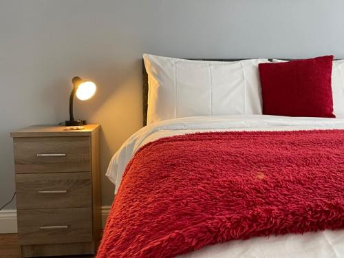 a bed with a red blanket and a night stand at Durham 3 Bedroom House With Parking in Durham