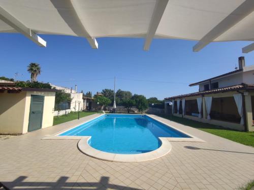 a large swimming pool in a yard with an umbrella at Villa Valeria in Floridia
