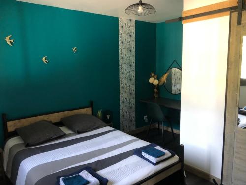 1 dormitorio con 1 cama con paredes azules y escritorio en Appartement cosy proche de la gare en Saint-Jean-de-Maurienne