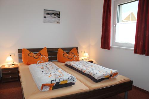 two beds with orange pillows on top of them at Haus Elisabeth in Gaschurn