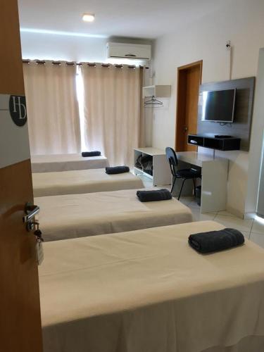 a room with four beds and a desk and a television at Domum Hotel in Pindamonhangaba