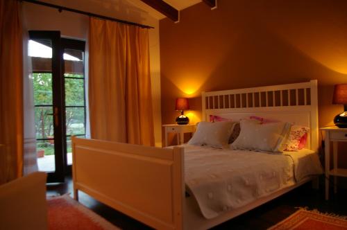 a bedroom with a white bed and a large window at Pensiunea La Dolce Vita in Băile Herculane