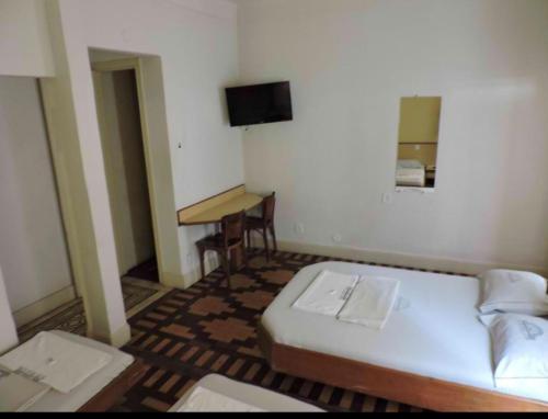 a small bedroom with a bed and a desk at Hotel Belas Artes in Rio de Janeiro