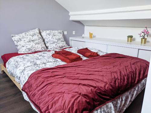 - une chambre avec un grand lit et des draps rouges dans l'établissement Rêves Paisibles Rubis - Choisy, à Choisy-le-Roi