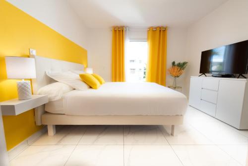 een slaapkamer met een bed en een tv en gele muren bij Eden Blue vue Mer et Piscine in Sainte-Anne