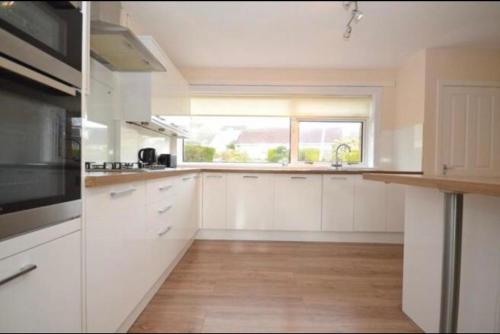 a kitchen with white cabinets and a window at Helensburgh homely accommodation in Helensburgh