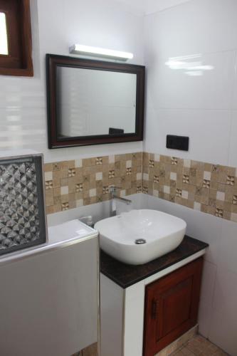W łazience znajduje się umywalka i lustro. w obiekcie White Elephant Villa & Restaurant w mieście Beruwala