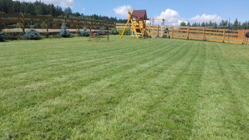 a playground with a slide in the middle of a field at Lawendowy Dworek in Laskówka