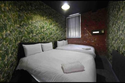 ein Schlafzimmer mit einem weißen Bett und einer grünen Wand in der Unterkunft Casa Jungle Slps 20 Mcr Centre Hot tub, bar and cinema Room Leisure suite in Manchester