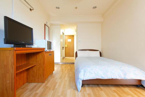 a bedroom with a bed and a flat screen tv at FLEXSTAY INN Tamagawa in Kawasaki
