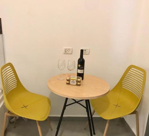 a table with two yellow chairs and a bottle of wine at Suites in the Galilee in Qiryat Shemona