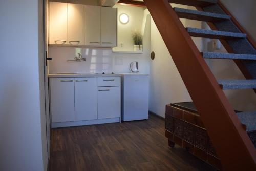 a kitchen with white cabinets and a staircase at Pension Elbrs in Mariánské Lázně