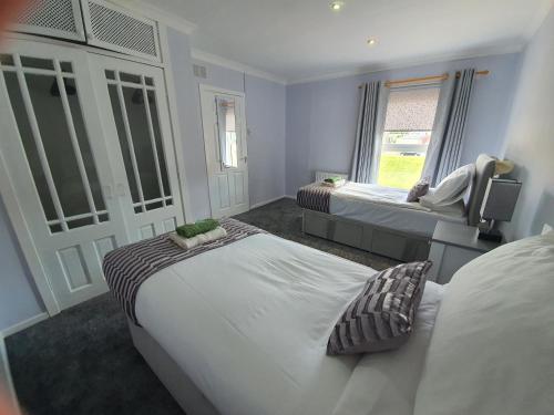 a bedroom with two beds and a tv in it at PREMIER - Kenilworth House in Holytown