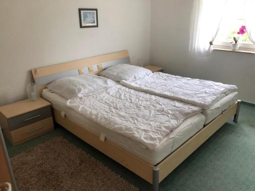 een slaapkamer met een bed met witte lakens en een raam bij Kapitänshaus Scharmberg, Ferienwohnung Seeadler in Born