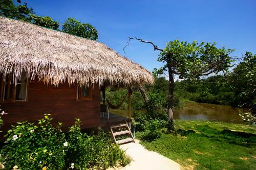 a small hut with a thatch roof and a pathway at Rabbit Bungalow in Ko Phayam