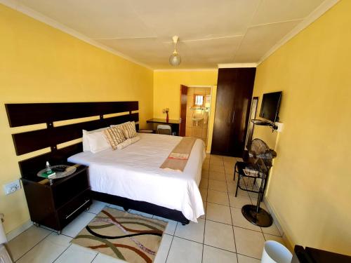 Katlego guest house في ولكوم: غرفة نوم بسرير كبير وجدران صفراء