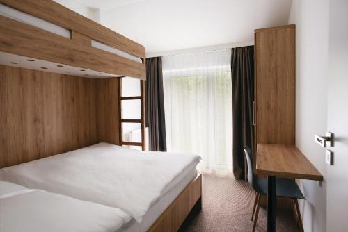 a bedroom with two beds and a desk and a window at Galeria Apartments - Jasná in Demanovska Dolina