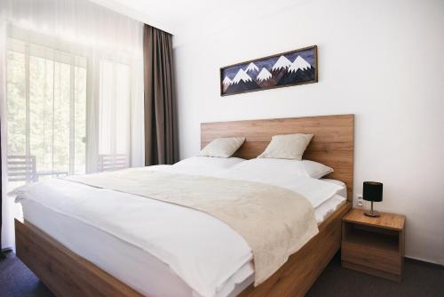 a bedroom with a large white bed and a window at Galeria Apartments - Jasná in Demanovska Dolina