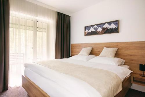 a bedroom with a large bed and a window at Galeria Apartments - Jasná in Demanovska Dolina