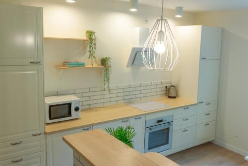 a kitchen with white cabinets and a microwave at Apartament Konopnickiej10 in Gdańsk