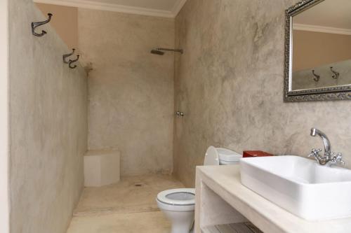 a bathroom with a sink and a toilet and a mirror at Jeffreys Guest Rooms in Jeffreys Bay