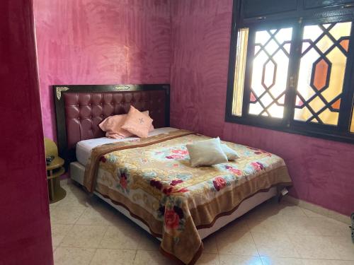 a bedroom with a bed with pink walls and a window at Appartement lumineux in Marrakesh