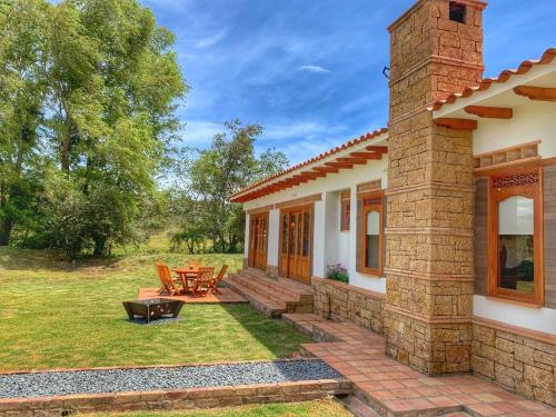 a house with a patio with a table and chairs at Casa de las Flores- Chalet Privado in Villa de Leyva