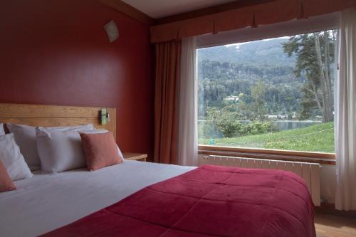 - une chambre avec un lit et une grande fenêtre dans l'établissement Costa Serena Apart Cabañas & Spa, à Villa La Angostura