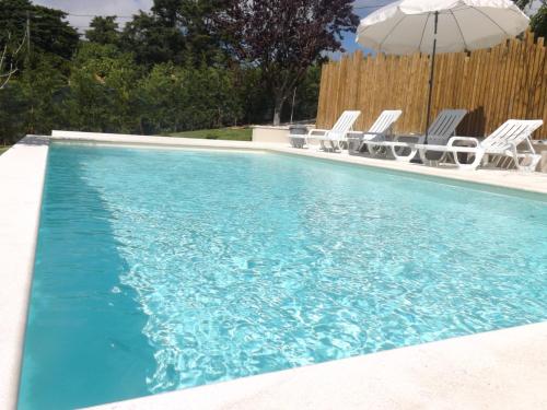a swimming pool with chairs and an umbrella at Casal do Pinheiro in Óbidos