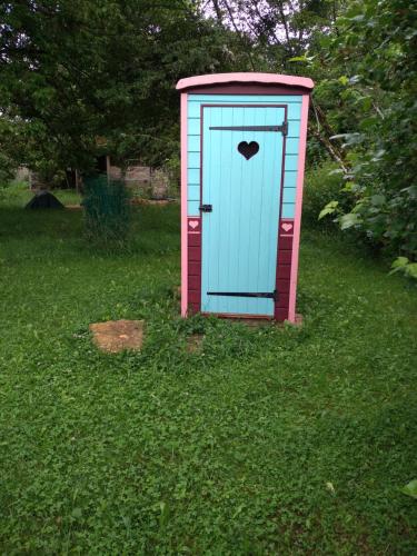 a outhouse with a blue door in the grass at Les roulottes in Pouilly-sur-Vingeanne
