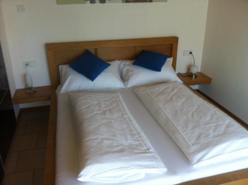 ein Bett mit zwei blauen Kissen darauf in der Unterkunft Ferienwohnung Schmid in Hagnau