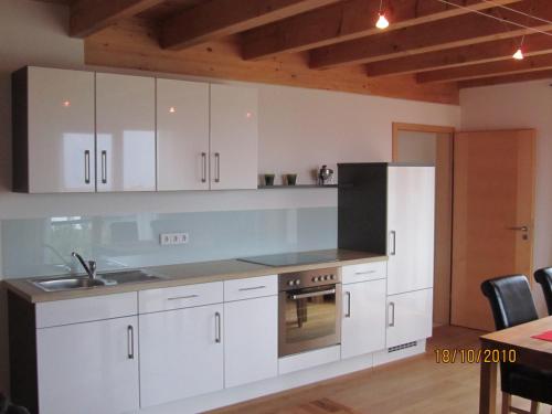 een keuken met witte kasten, een wastafel en een fornuis bij Ferienwohnung Schmid in Hagnau