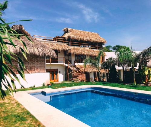 a house with a swimming pool in front of a building at Hotel el Risco in Cuatunalco