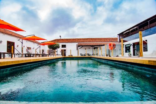 een zwembad voor een gebouw met oranje parasols bij Hotel Rural Jardines de Milano in Los Realejos