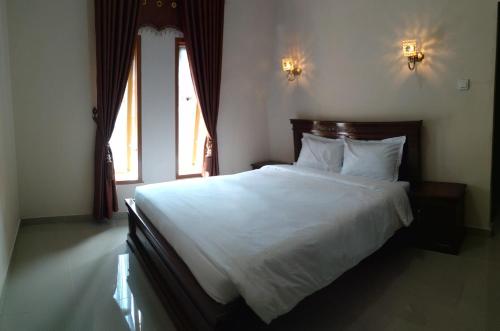 a bedroom with a large white bed with two windows at Baringin Anam Guest House Syariah in Baso