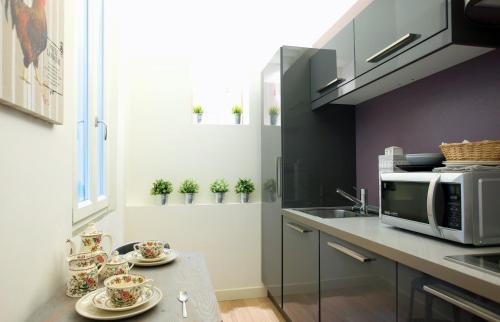 a kitchen with a table with plates and a microwave at Parmigianino Nove in Parma