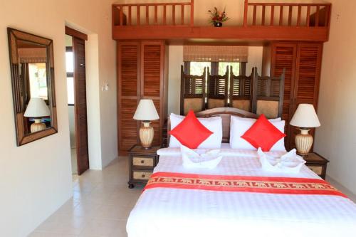 1 dormitorio con 1 cama grande con almohadas rojas en Baan KanTiang See Villas - SHA Extra Plus, en Ko Lanta