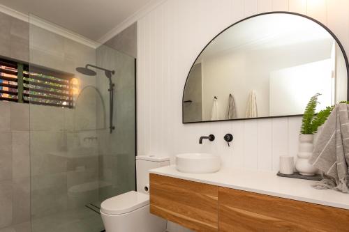 y baño con aseo, lavabo y espejo. en Casuarina Cove Apartments en Isla Hamilton