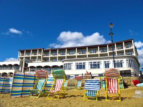 un grupo de sillas en la playa frente a un edificio en Sandringham Hotel - Seafront, Sandown --- Car Ferry Optional Extra 92 pounds Return from Southampton, en Sandown
