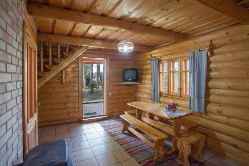 a log cabin dining room with a table and a tv at Atpūtas komplekss Godeļi in Usma