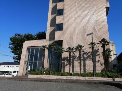 a building with palm trees in front of it at Hotel Areaone Minamisoma in Haranomachi