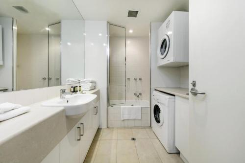 La salle de bains blanche est pourvue d'un lavabo et d'un lave-linge. dans l'établissement Portsea Village Resort, à Portsea