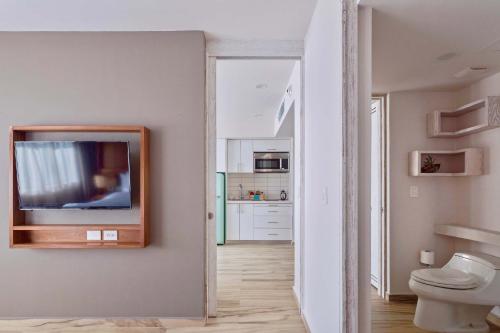 a bathroom with a toilet and a tv on a wall at Newport House Playa Boutique Hotel in Playa del Carmen