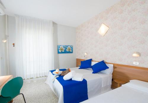 a bedroom with two beds with blue pillows at Hotel Gaudia in Riccione