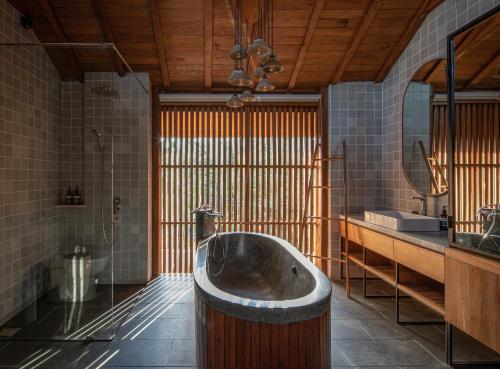 uma casa de banho com banheira no meio de um quarto em Tekuni 2 em Legian