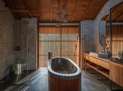 a bathroom with a tub in the middle of a room at Tekuni 2 in Legian