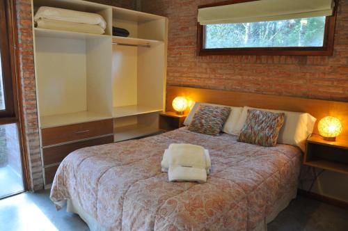 1 dormitorio con 1 cama con 2 luces y una ventana en Cabañas Abril, en Mar de les Pampas